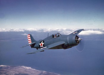 One-quarter front right side view of U. S. Navy Grumman F4F-4 Wildcat in flight over a shoreline, probably somewhere over Long Island, New York.